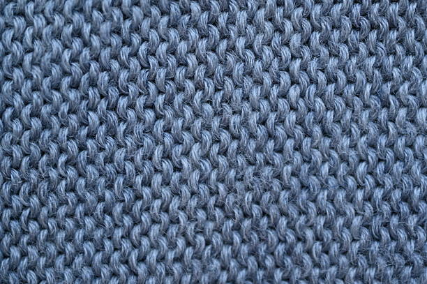 gray woolen fabric texture as a background, macro texture of gray crocheted sweater as a background, close-up of gray crocheted front surface, woolen texture of acrylic synthetic  crocheted