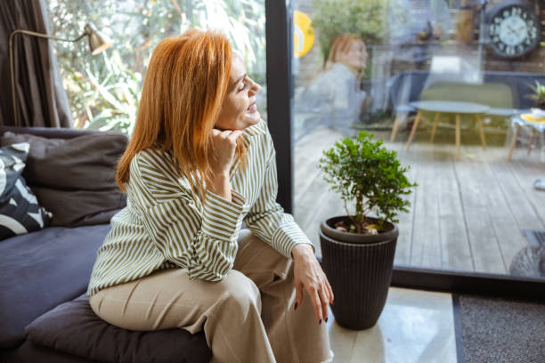 istock Woman sitting on a couch in a bright and modern living space 2201862673