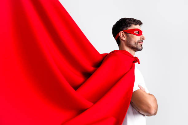 istock Confident Young Man Wearing Red Cape and Mask in Heroic Pose on White Background Symbolizing Heroism and Inspiration 2201864328