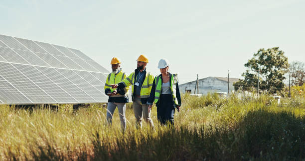 istock People, discussion and technician with team for solar panel installation, photovoltaic development or PV project. Group, engineer or contractors walking with helmet for renewable energy or power 2201865204