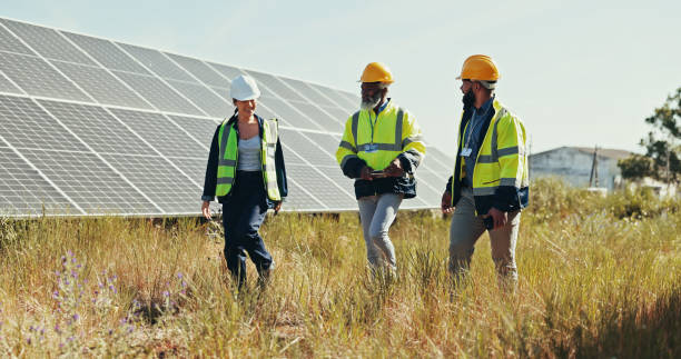 Business people, technician and walking with team for solar panel installation, photovoltaic development or project in nature. Group, engineer or contractors with helmet for renewable energy or power