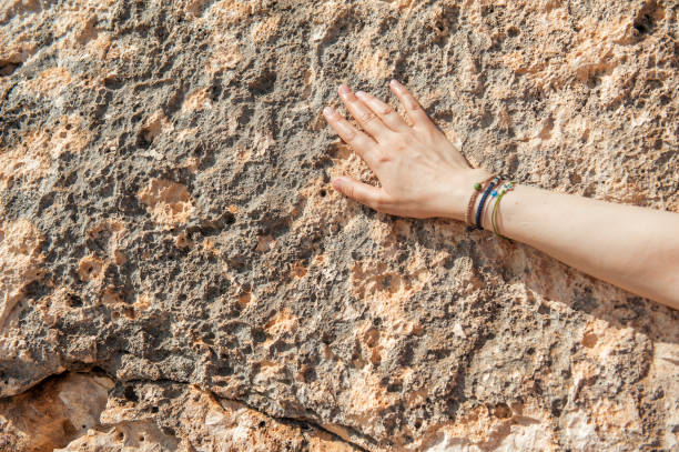 Woman hand with different bracelets on the old stone wall background
