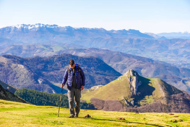 Hiker walking on a mountain path, enjoying the stunning views of the txindoki peak and the surrounding landscape