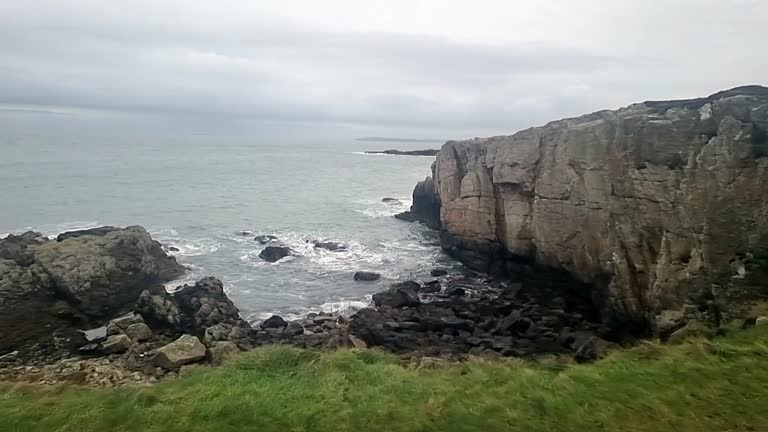 Rugged fractured Welsh Anglesey coastline overlooking cold windy seascape waves and tide pan left