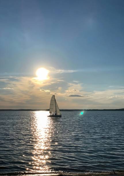 istock boat with a white sail on a sunny summer evening in backlight and on a sunny path of reflected light 2201869061