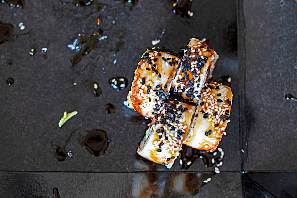 sushi rolls with eel pieces and shrimps with a sprig of sprouted peas in open packaging