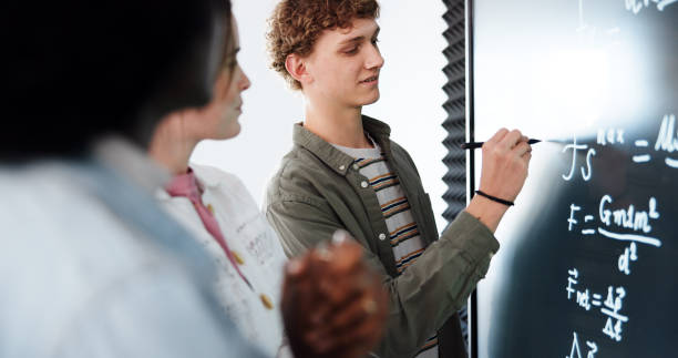 istock Education, students and people with formula, smart board or revision for exam in classroom or online. Learning, pupil and group in university for knowledge, digital or writing for practice of physics 2201869887
