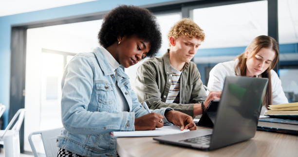 istock Education, group and students with laptop, classroom and research for assignment in college or writing. University, learning and people with tech for knowledge, studying and teamwork for project 2201869906