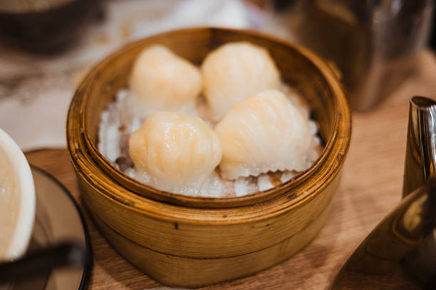 An Asian woman is enjoying Chinese dim sum shumai in restaurant