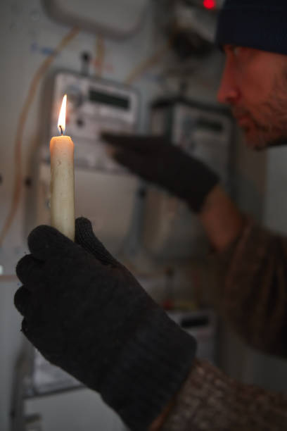 istock Checking the electricity power meter with a candle in cold winter days while there is power outage. 2201871494