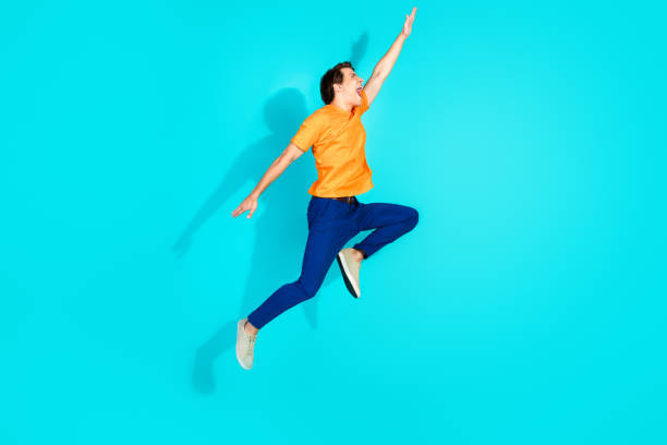 istock Energetic young man jumping excitedly against a bold teal background showcasing vibrant energy and dynamic action 2201871746