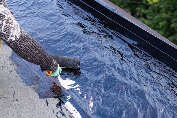 a young worker treats a roof with bitumen primer before applying rolled asphalt roofing using a torch