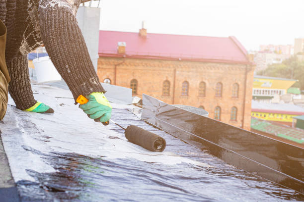 a young worker treats a roof with bitumen primer before applying rolled asphalt roofing using a torch