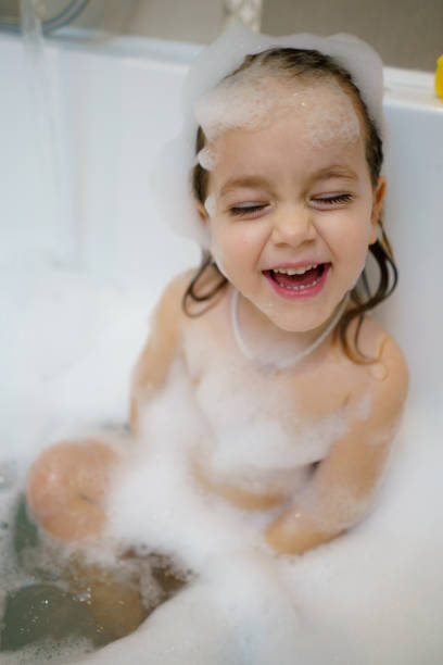 A little girl enjoys a bubble bath in the bathroom