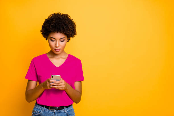 istock Copyspace photo of attractive thinking guessing puzzled black girlfriend browsing through her telephone wearing jeans denim t-shirt while isolated over yellow vivid color background 2201875275