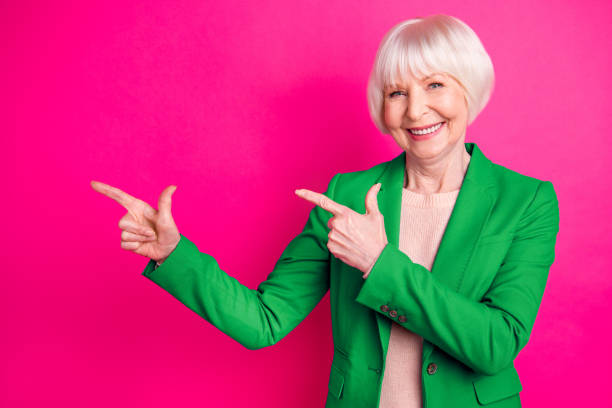 istock Portrait of her she nice-looking attractive lovely representative elegant classy cheerful glad gray-haired lady pointing aside ad isolated over bright vivid shine vibrant pink fuchsia color background 2201877623