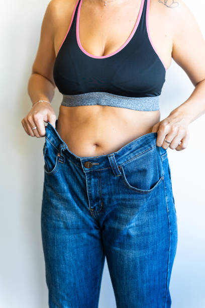 istock Woman showing weight loss by wearing old jeans 2201877862