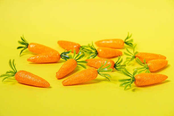 istock easter holiday decoration with artificial glittery carrots scattered on a bright yellow background, symbolizing spring, freshness, and festive joy 2201878280