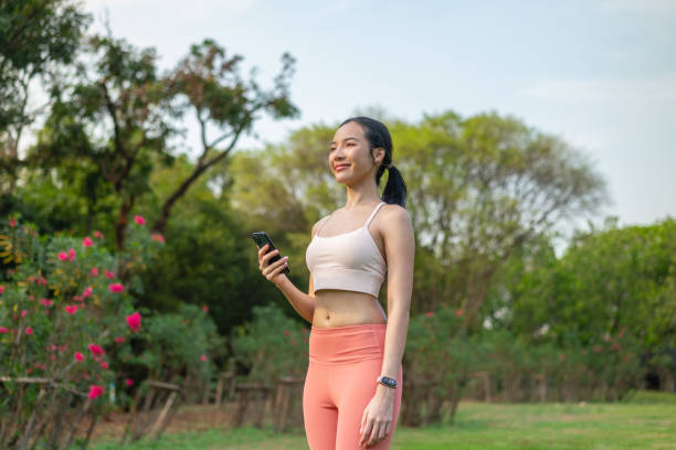 istock Young Asian Woman Using Phone During Outdoor Workout In a Park 2201878373