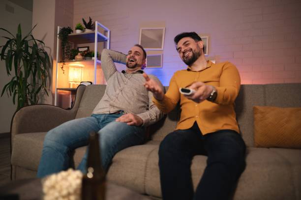 istock Two friends laughing while watching television at home 2201878874