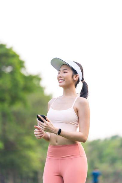 istock Young Asian Woman with Visor Cap Using Phone While Exercising Outdoors In a Park 2201879167