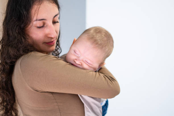 istock Mother gently holding sleeping baby at home 2201879230