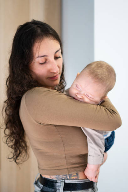 istock Mother gently holding sleeping baby in arms 2201879237