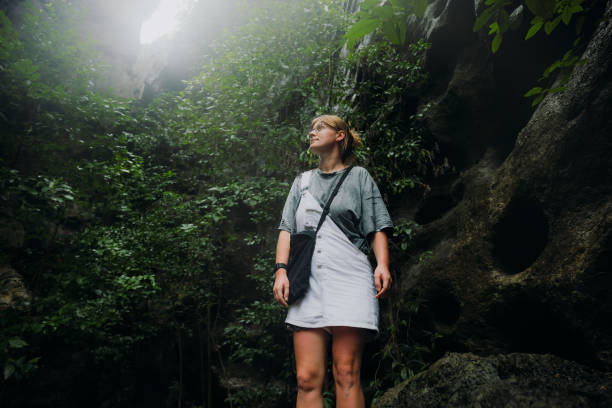 Low-angle view of woman explorer staying in the cave in rainforest on Flores Island, Indonesia