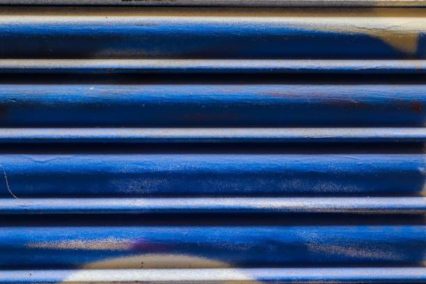 istock Blue metal shutter showing signs of wear and graffiti marks 2201881509