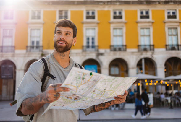 istock Smiling tourist holding a map and exploring lisbon, portugal 2201884565
