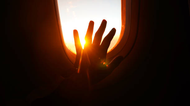 istock sunrise viewed from an airplane window with hands reaching towards the light 2201891087