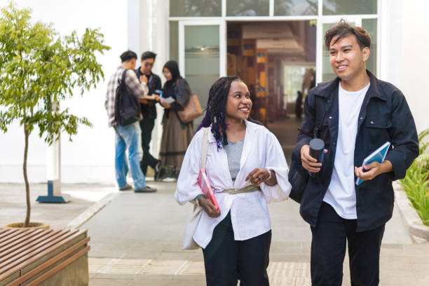 istock Happy Asian college classmates leaving school talking together, walking outside 2201892111