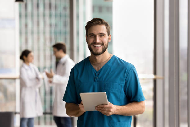 istock Young handsome man medical worker in scrubs holding digital tablet 2201893804