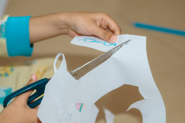 close up of a child's hand cutting paper, selective focus