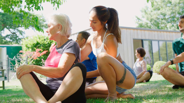 istock Female Instructor Helping Students At Outdoor Yoga Class 2201894305
