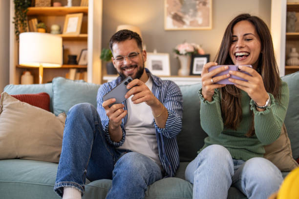 istock Couple having fun, playing games on their smartphones 2201894477