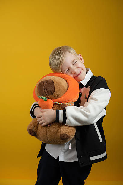 istock A little boy with a soft capybara toy on a yellow background. 2201897863