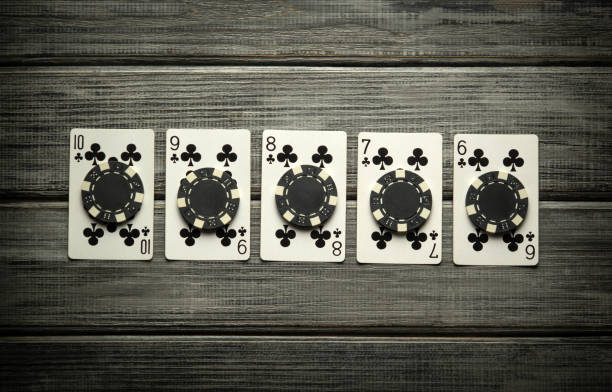 istock Five playing cards are arranged in a row on a rustic wooden table, reflecting the excitement of a high-stakes poker game. The light casts soft shadows, enhancing the atmosphere of anticipation 2201898139