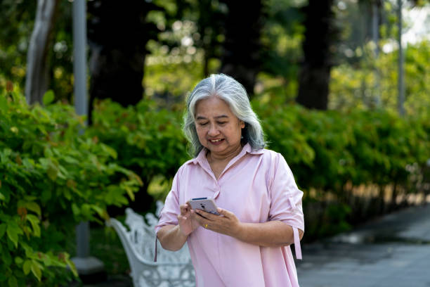 istock Senior woman using mobile phone during walking in park 2201899286