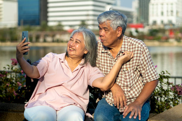 istock Asian Elderly Couple Enjoy with smartphone while relax together at city Park 2201899477
