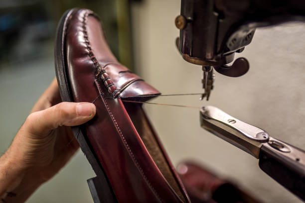 istock Skilled craftsman mending leather shoe using vintage sewing machine, showcasing meticulous repair work in traditional workshop setting 2201900687