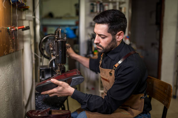 Shoemaker carefully examining a leather shoe while working on a vintage sewing machine in his traditional workshop, showcasing craftsmanship and attention to detail