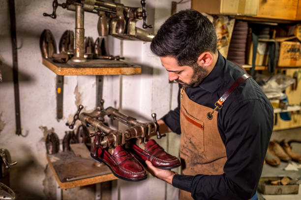 istock Skilled cobbler crafting high-end leather loafers with precision, surrounded by vintage tools in traditional workshop highlighting artisan shoemaking expertise 2201901317