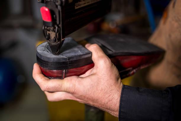 istock Skilled cobbler repairing red shoe sole using pneumatic stapler, showcasing traditional leather crafting techniques in workshop 2201901331