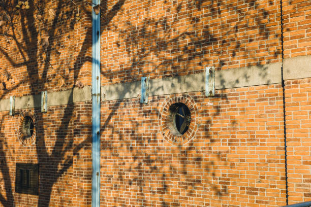 Sunlight illuminates one wall of the red brick house