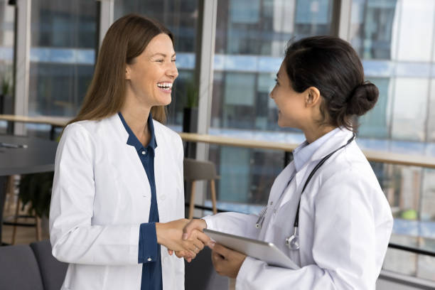 istock Doctors shaking hands, having friendly informal talk in clinic 2201903671