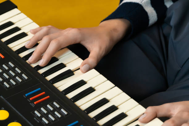 istock Capturing the essence of creativity, musician's hands skillfully playing a vintage synthesizer keyboard, generating electronic music against a vibrant yellow backdrop 2201905495