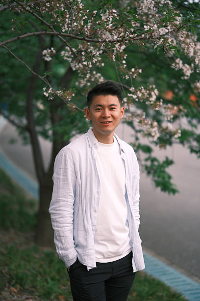 istock smiling Asian young with sakura blossom, looking at camera 2201908852