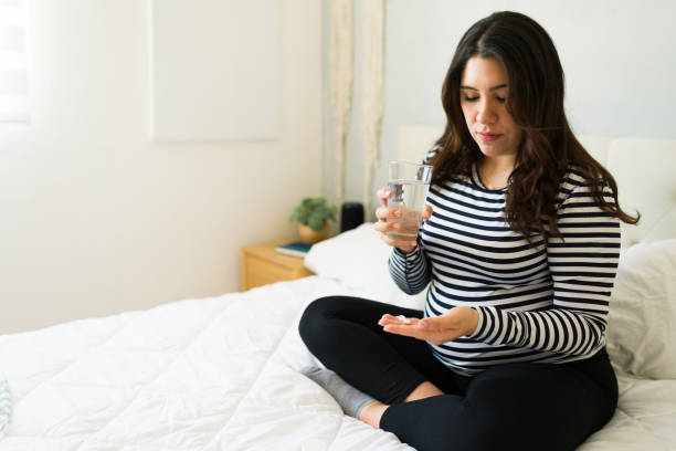 istock Expectant mother swallowing medication, drinking water while managing prenatal health concerns 2201910802