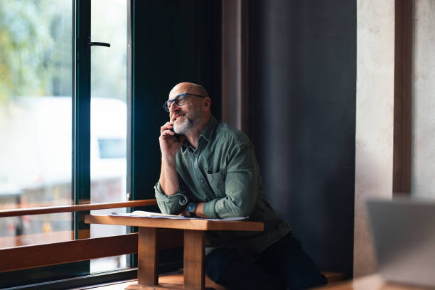 istock Man Talking on Phone in a Sunlit Cafe Interior 2201911209